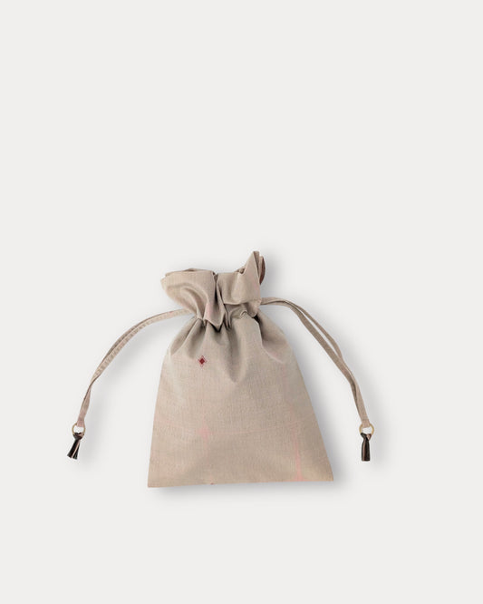 A small beige fabric drawstring pouch with a drawstring closure and a tiny red embroidered star on the front, shown against a light gray background.