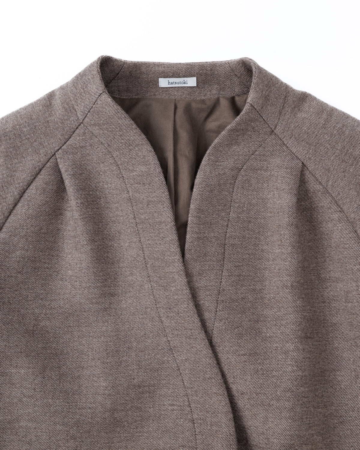 Close-up of a taupe-brown jacket with a brand label on a white background