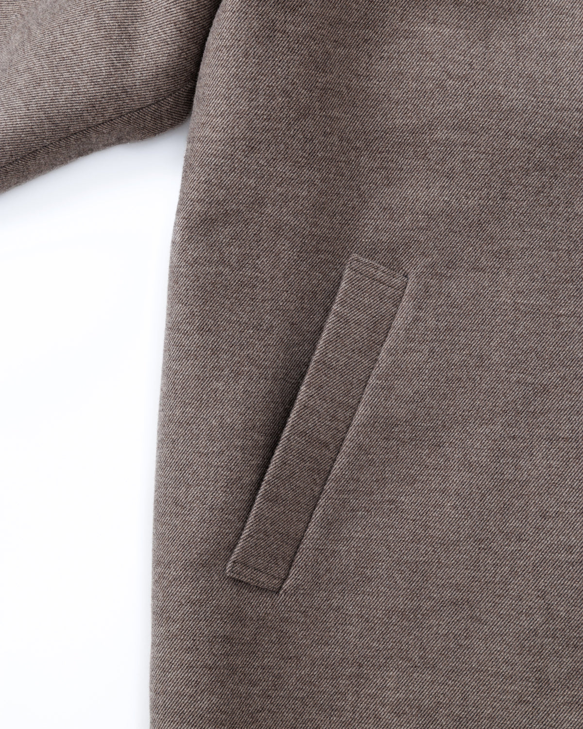Close-up of a taupe-brown coat with a patch on a white background