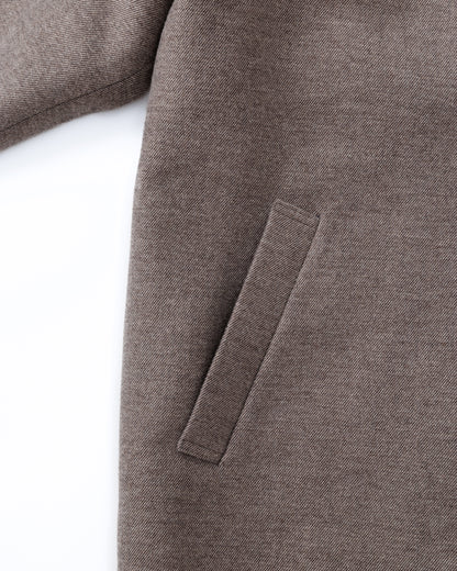 Close-up of a taupe-brown coat with a patch on a white background