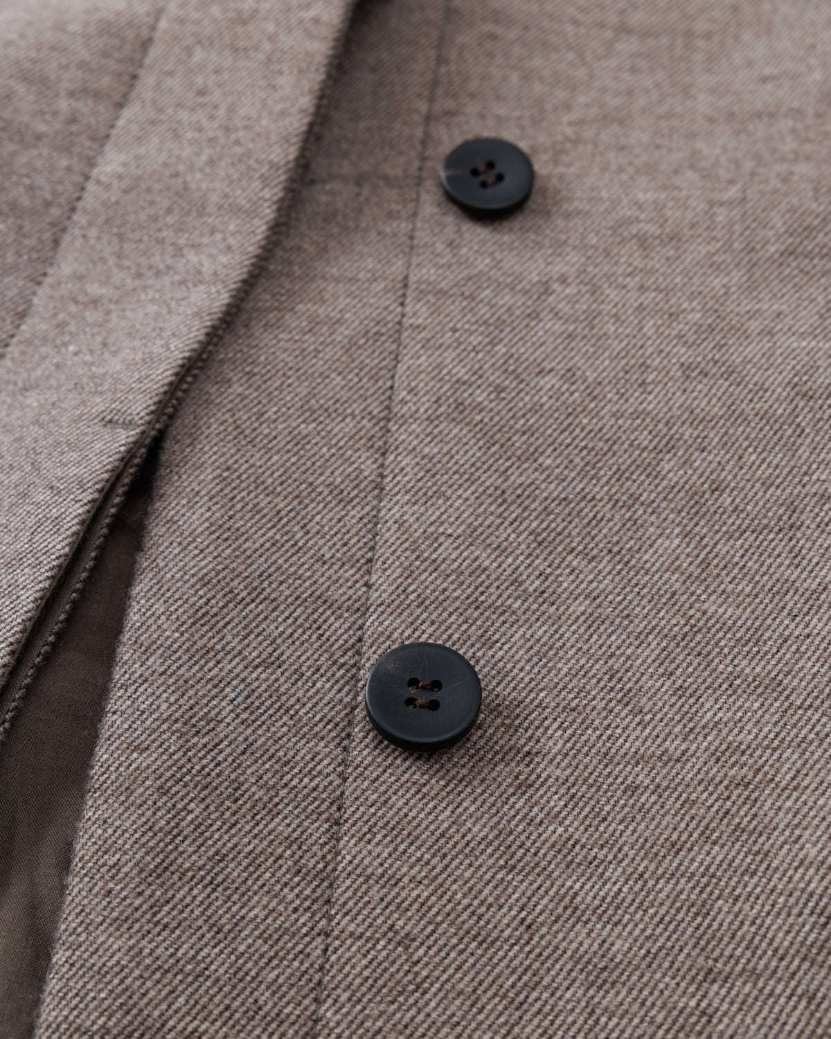 Close-up of a taupe-brown textured fabric with black buttons