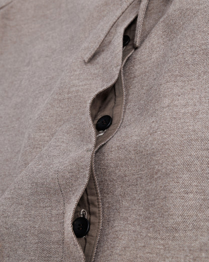 Close-up of a taupe-brown fabric with buttons and ruffled details