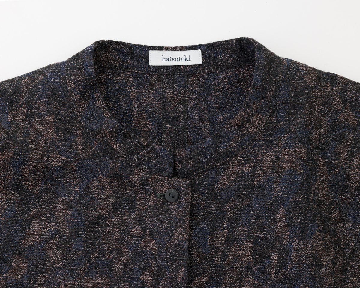 Close-up of a dark patterned shirt with a brand label on a white background