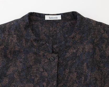 Close-up of a dark patterned shirt with a brand label on a white background