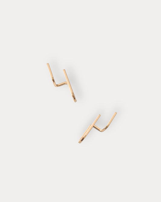 A pair of minimalist 14KGF gold-toned geometric stud earrings with a double-prong design, displayed on a clean, light gray background.