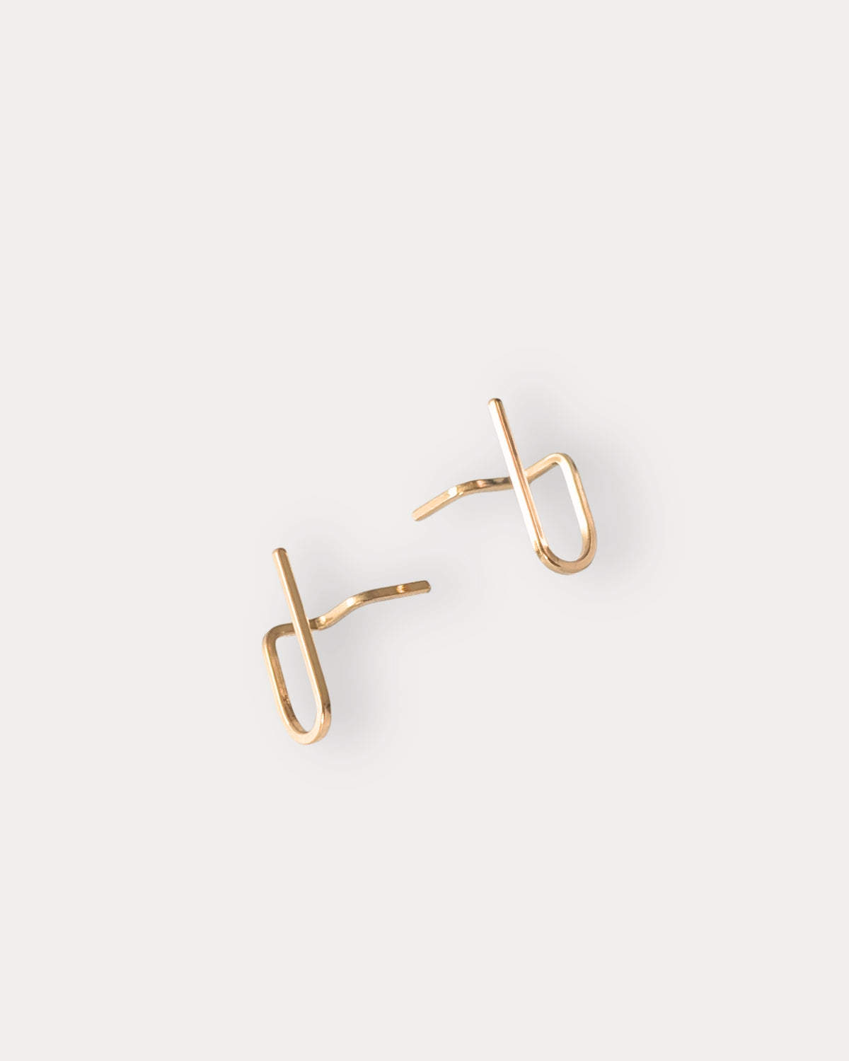 A pair of minimalist 14KGF gold-toned unique earrings with straight post backings, displayed on a clean, light gray background.