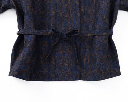 Detail of the waist of a navy shirt-jacket with a subtle pattern and a drawstring on a white background