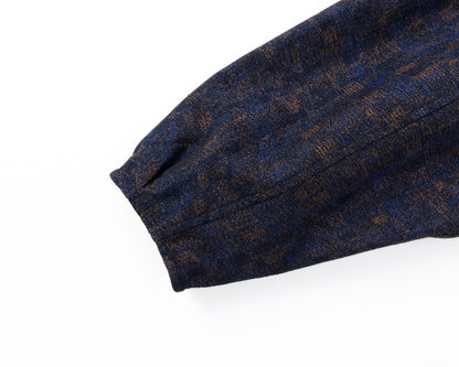 Detail of the sleeve of a navy shirt-jacket with a subtle pattern on a white background