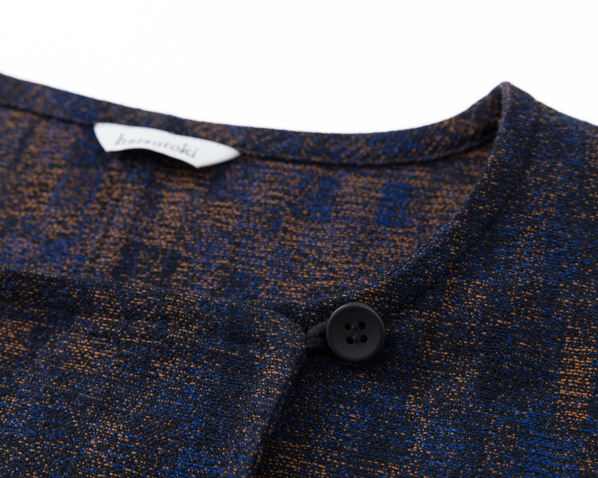 Close up of the top of a navy shirt-jacket with a subtle pattern on a white background