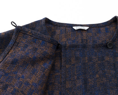 Close-up of a navy and brown patterned garment with a brand label on a white background