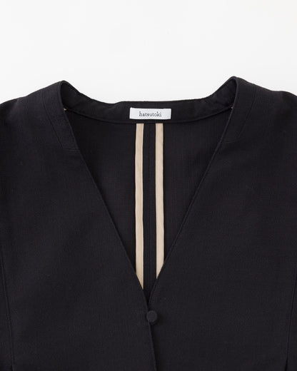 Close-up of a black V-neck top with two vertical beige stripes down the center front and a visible brand label at the collar reading harajuku.
