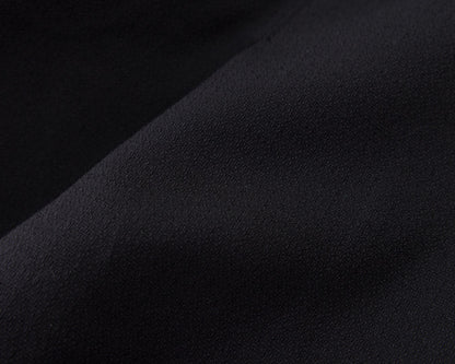 A close-up of a dark fabric surface with soft folds and a matte texture, shown in very dark navy-black tones.