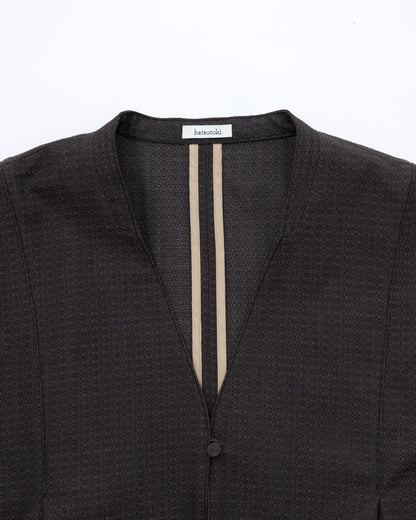 Close-up of a dark textured jacket with a V-neckline, featuring two vertical beige stripes down the centre front and a single button closure.