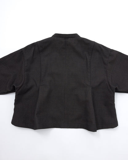 A black cropped jacket with a subtle textured pattern, shown from the back on a plain white background.