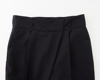 Close-up of black tailored trousers showing the waistband, front pleats, and side pockets against a plain white background.