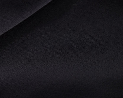 A close-up of a dark solid fabric surface with a soft diagonal fold, showing a very dark navy or near-black textile texture.