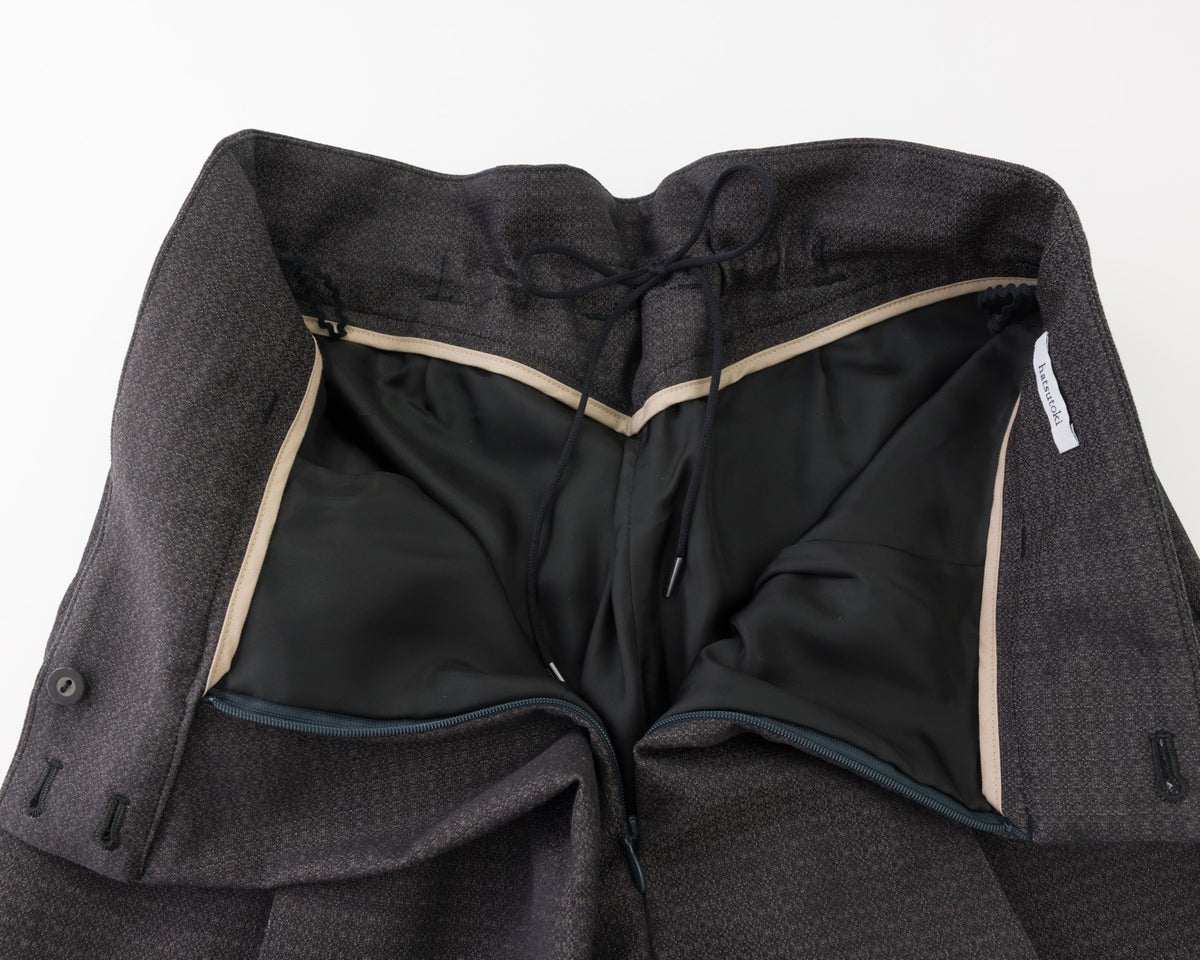 Close-up of black textured wool trousers showing the inner waistband lining.