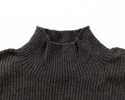 Close-up of a black ribbed knit turtleneck sweater on a plain white background.