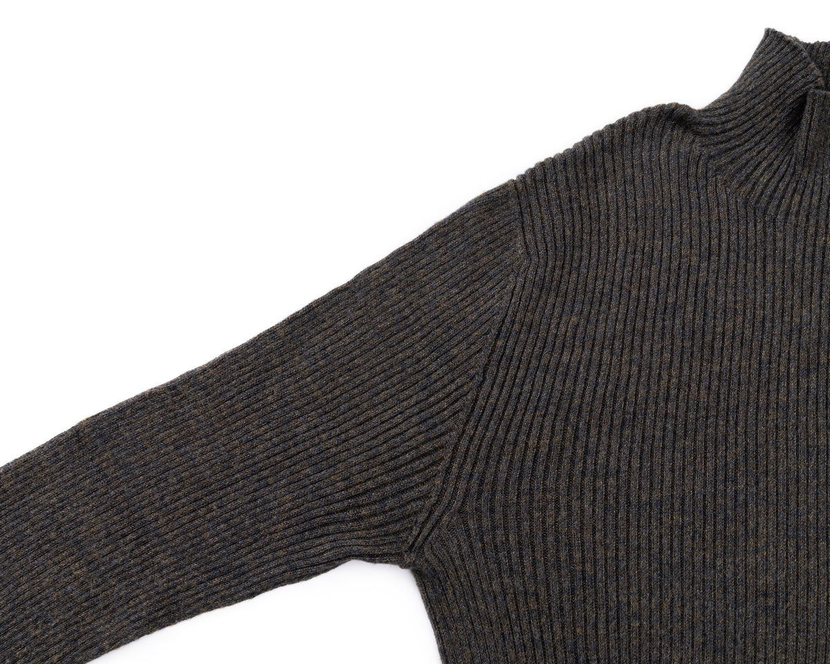 Close-up of a black ribbed knit turtleneck sweater sleeve and shoulder on a white background.