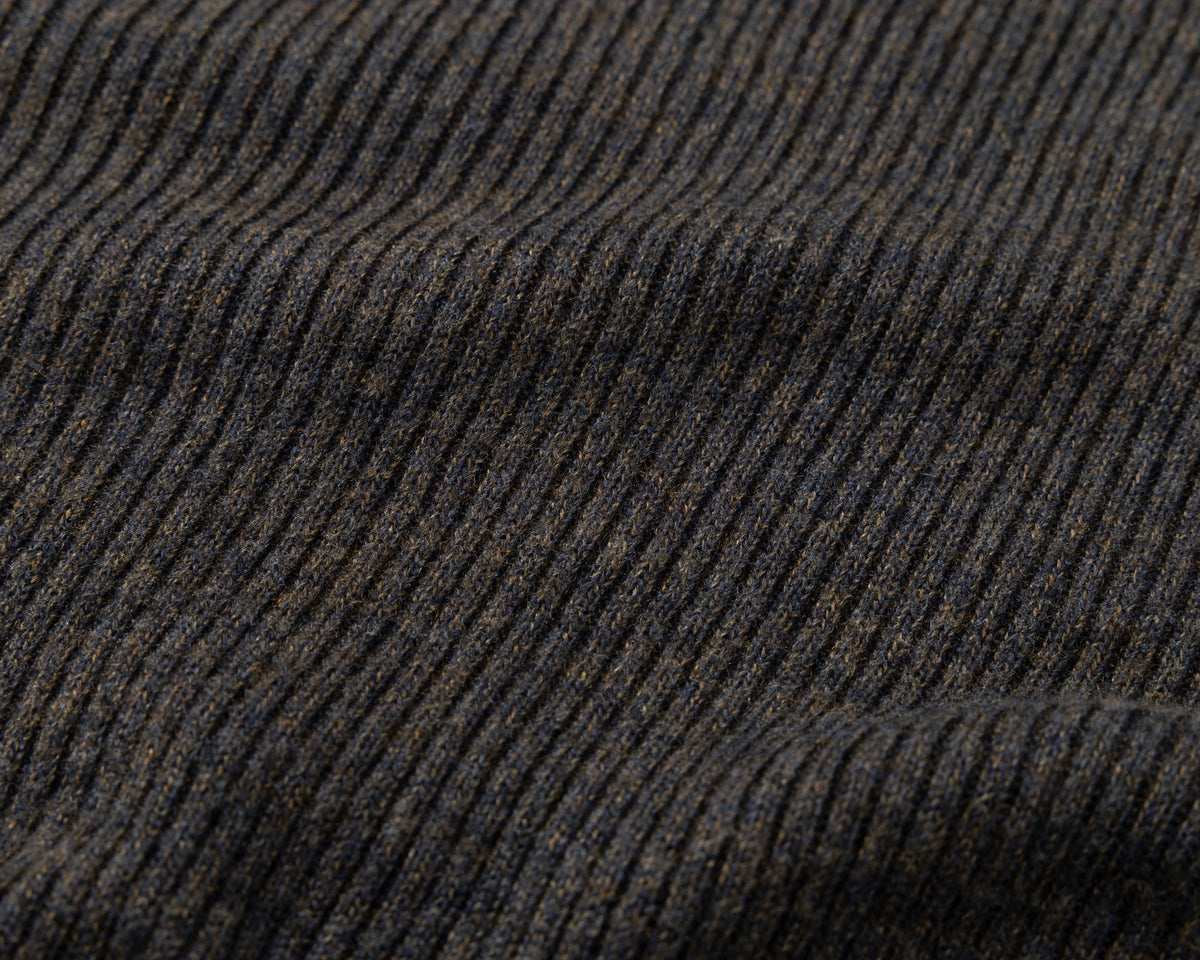 Close-up of a dark ribbed knit fabric with vertical ridges in black and brown tones.