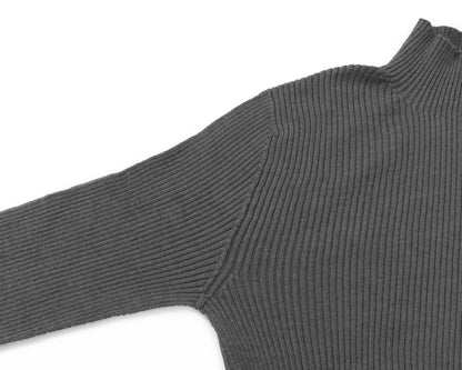 Close-up of a grey ribbed knit turtleneck sweater showing the shoulder seam and sleeve on a white background.