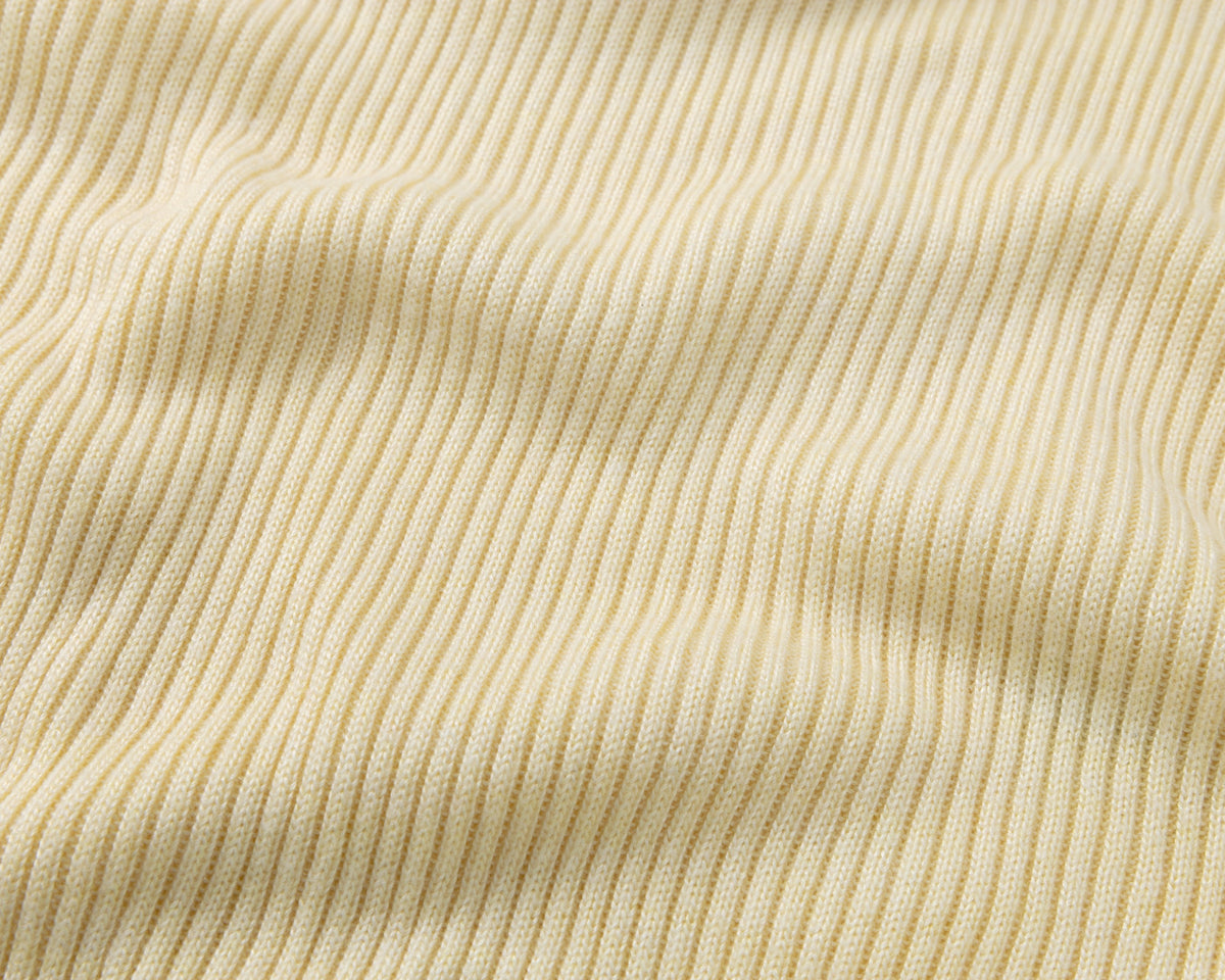 Close-up of a ribbed knit fabric in a light yellow colour, showing the vertical rib texture and soft folds.
