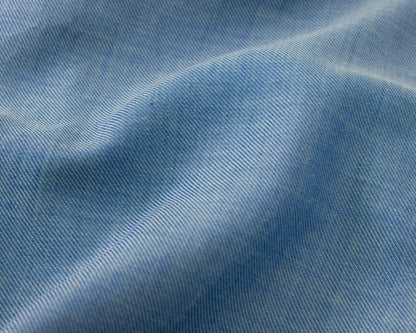 A close-up of light blue fabric with a fine diagonal twill texture and soft folds.