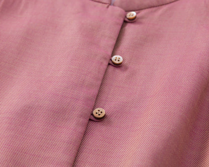 Close-up of a pink fabric with buttons on a matching pink background