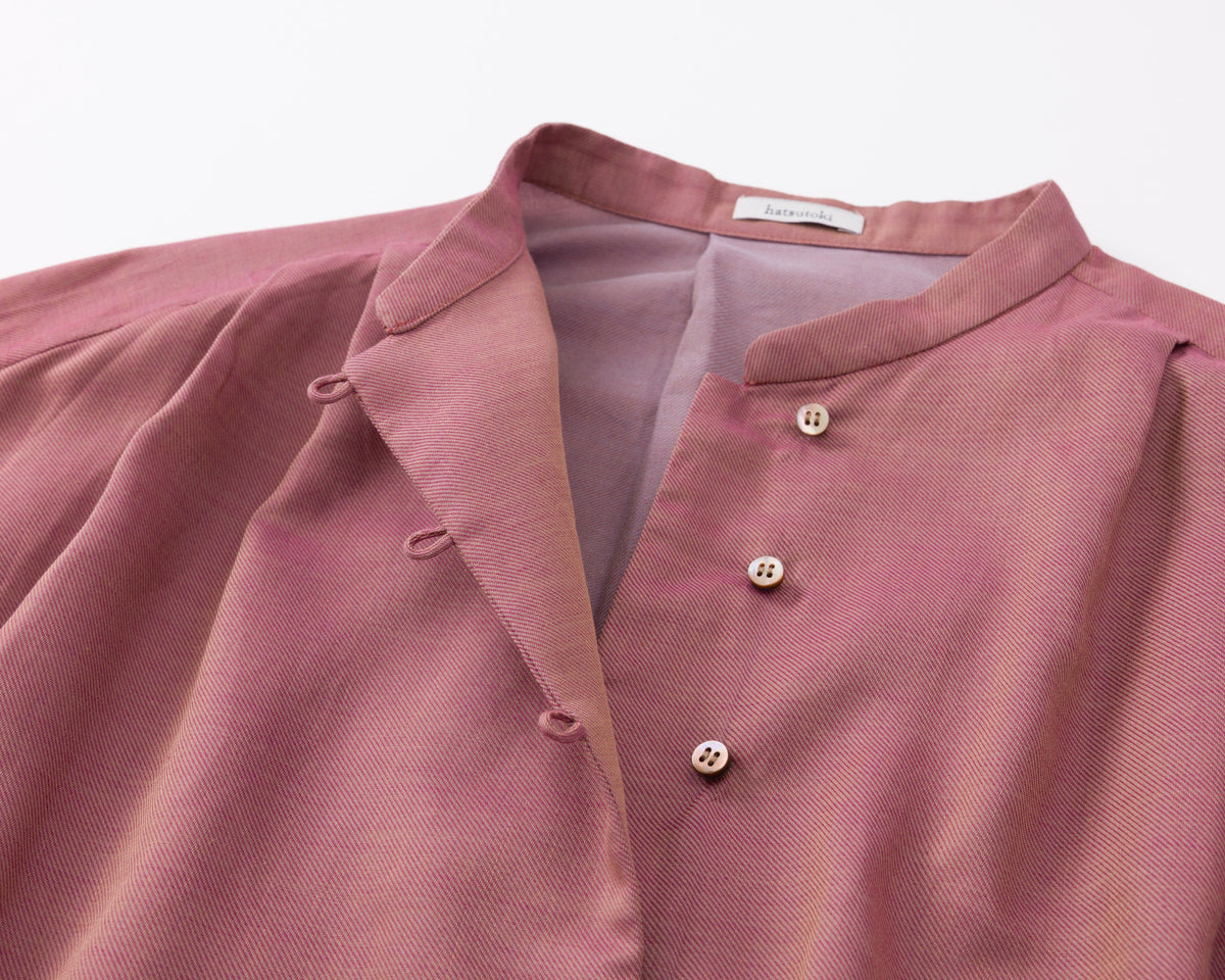 Close-up of a pink shirt with buttons on a light grey background