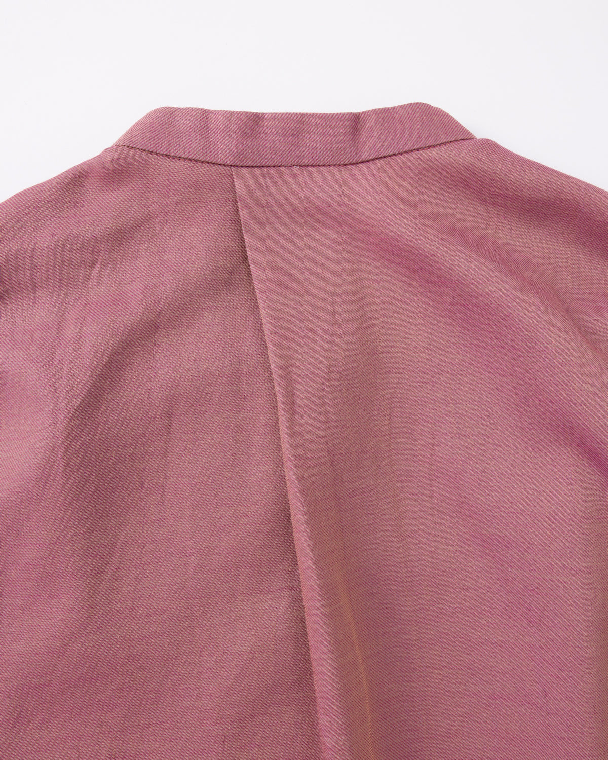 Close-up of a pink textured fabric with a collar on a white background