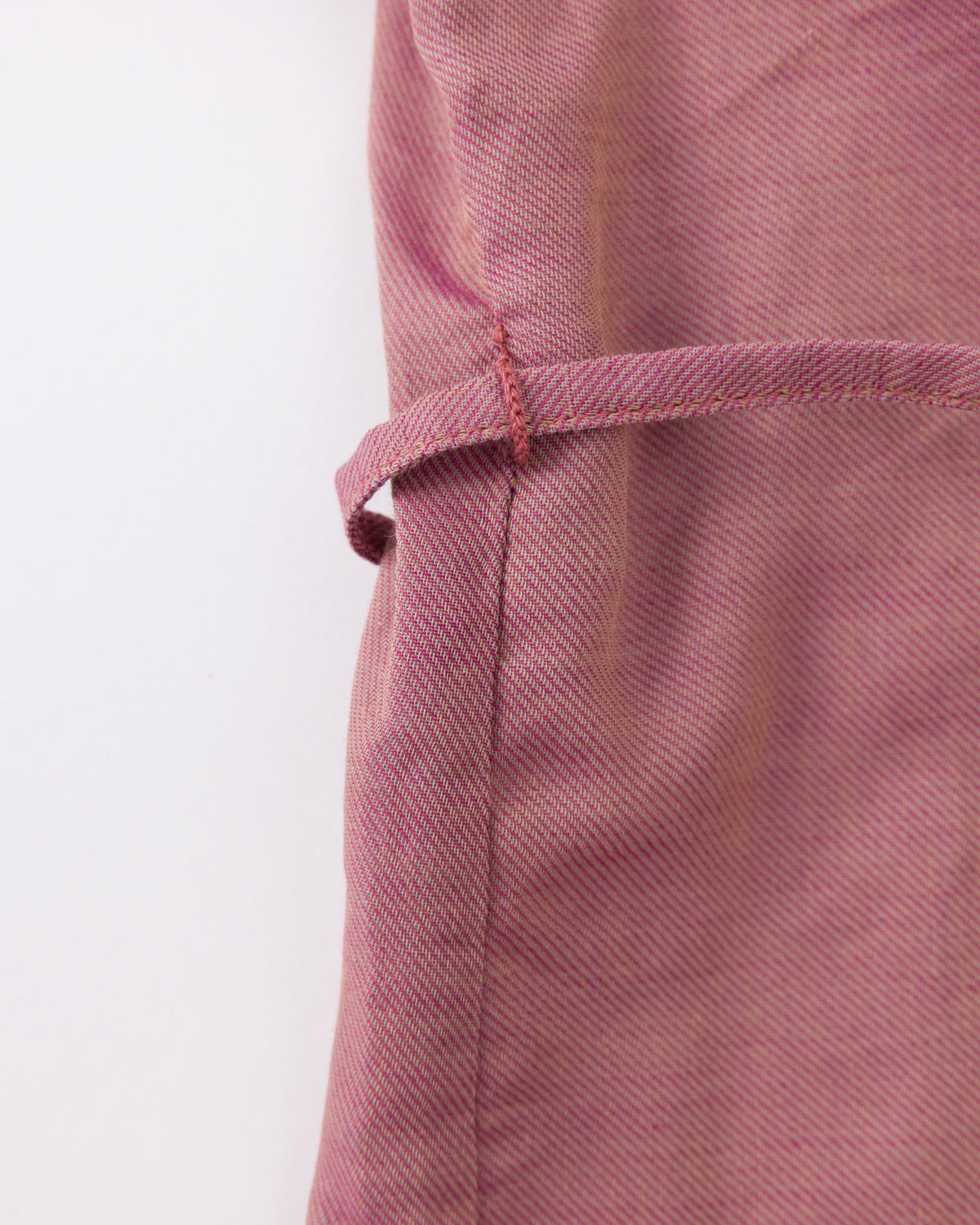 Close-up of a pink fabric with a visible seam on a white background