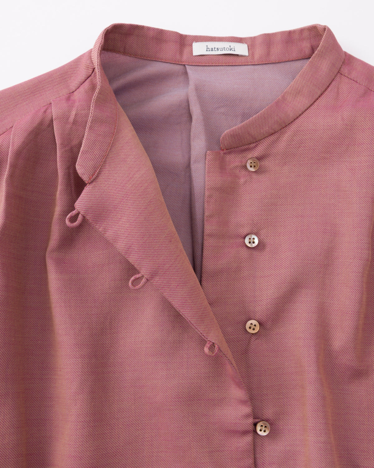 Close-up of a pink shirt with a brand label on a white background
