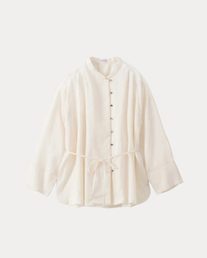 An off-white long-sleeve cotton shirt with a mandarin collar, button-down front, and a drawstring tie at the waist, displayed against a solid off-white background.