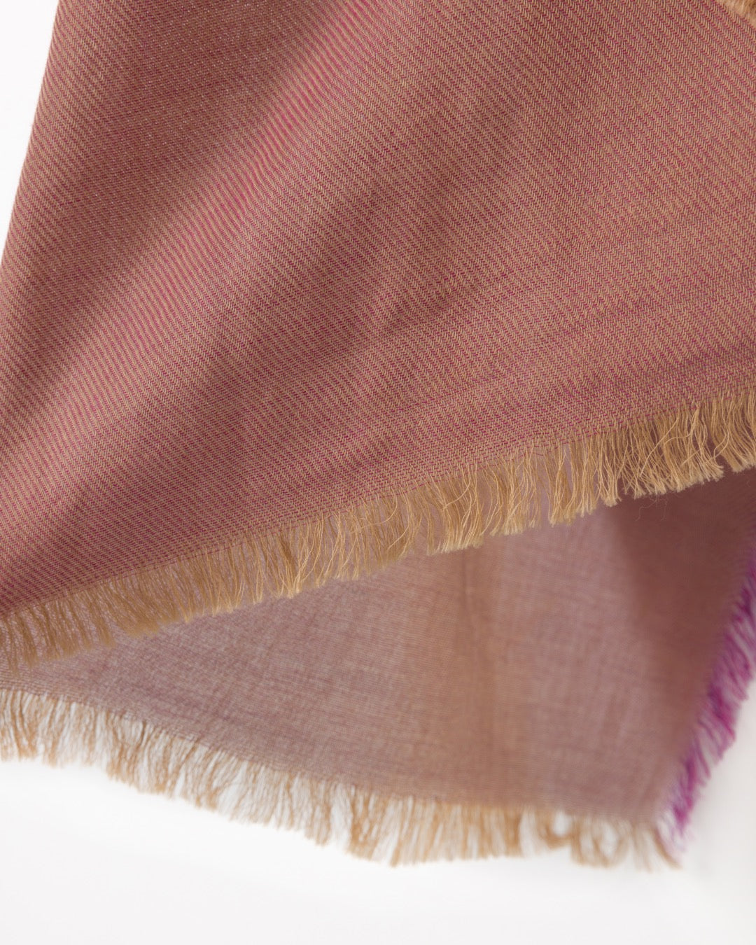 Detail of a dark pink scarf with purple and gold trims against a white background