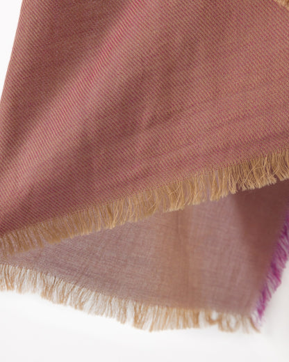 Detail of a dark pink scarf with purple and gold trims against a white background