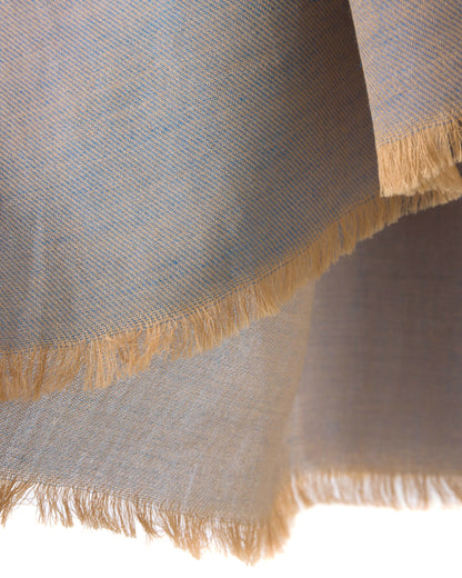 Detail of a grey scarf with blue accents and gold trims on a white background