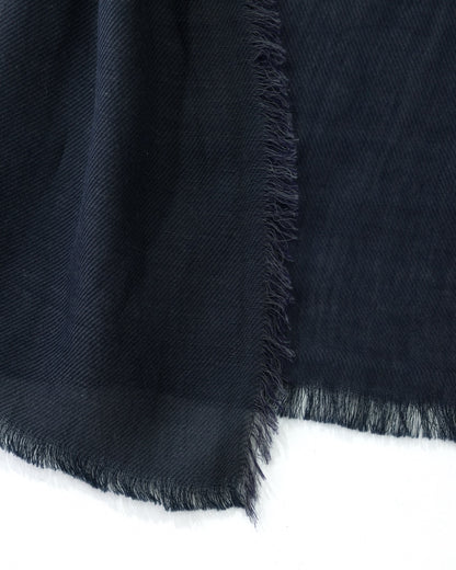 Detail of a navy scarf with trims on a white background