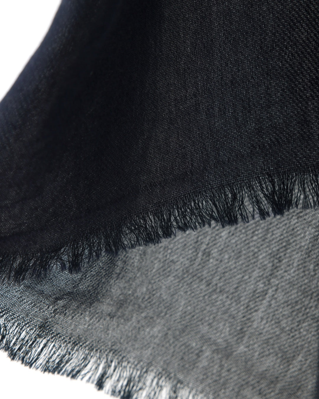 Detail of a navy scarf with trims on a white background