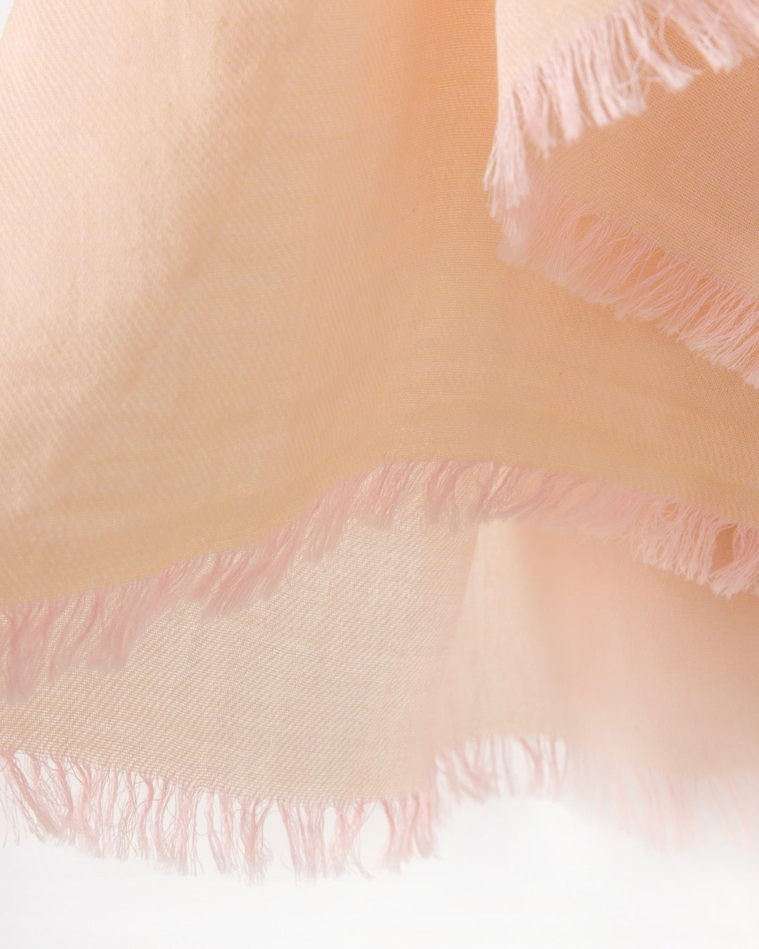 Detail of an orange scarf with pink trims on a white background
