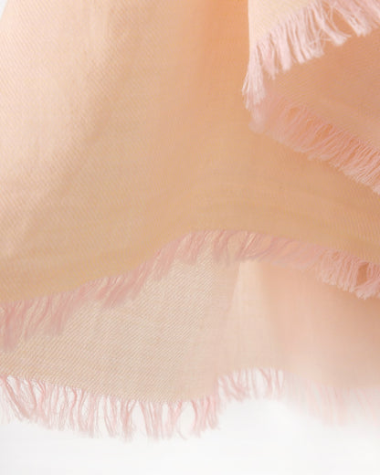 Detail of an orange scarf with pink trims on a white background