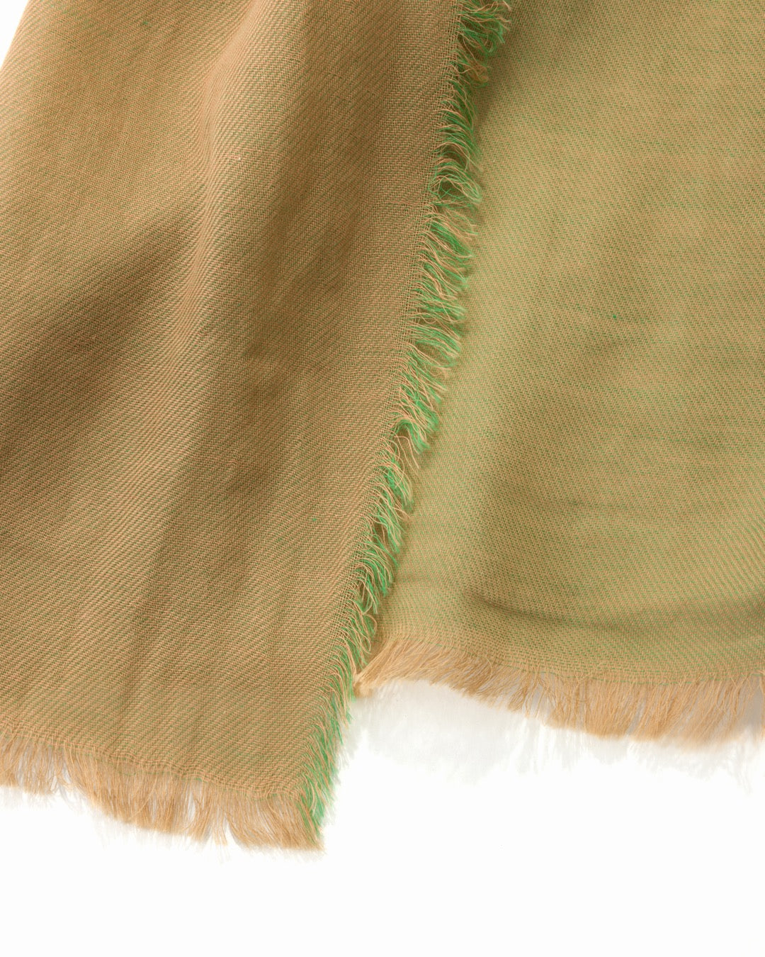 Detail of a pistachio green scarf with green and brown trims on a white surface.