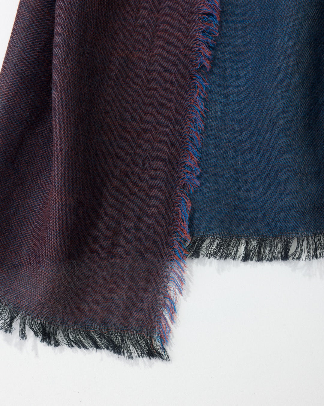 Close-up of a dark blue and purple scarf with frayed edges on a white background