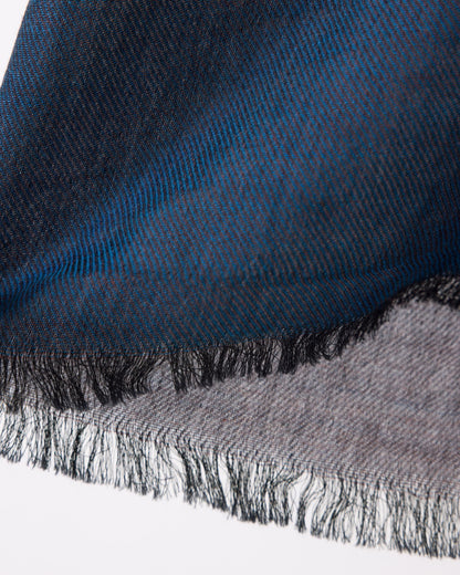 Close-up of a blue and gray scarf with fringed edges on a white background