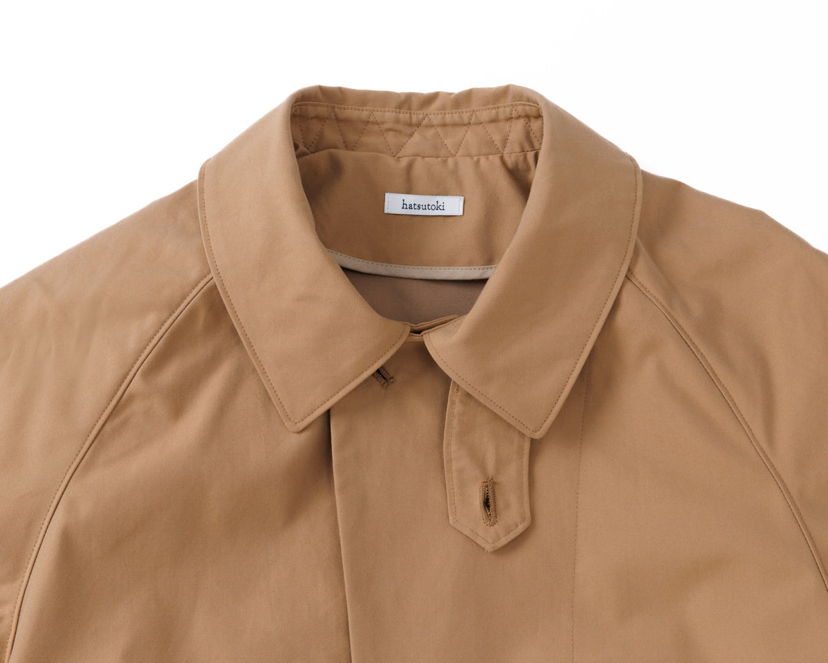 Detail of the collar of a beige car coat on a white background