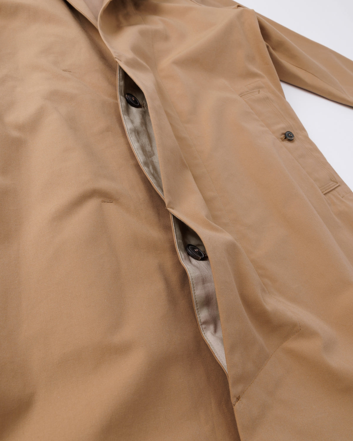 Close-up of a beige car coat with a button and collar detail.